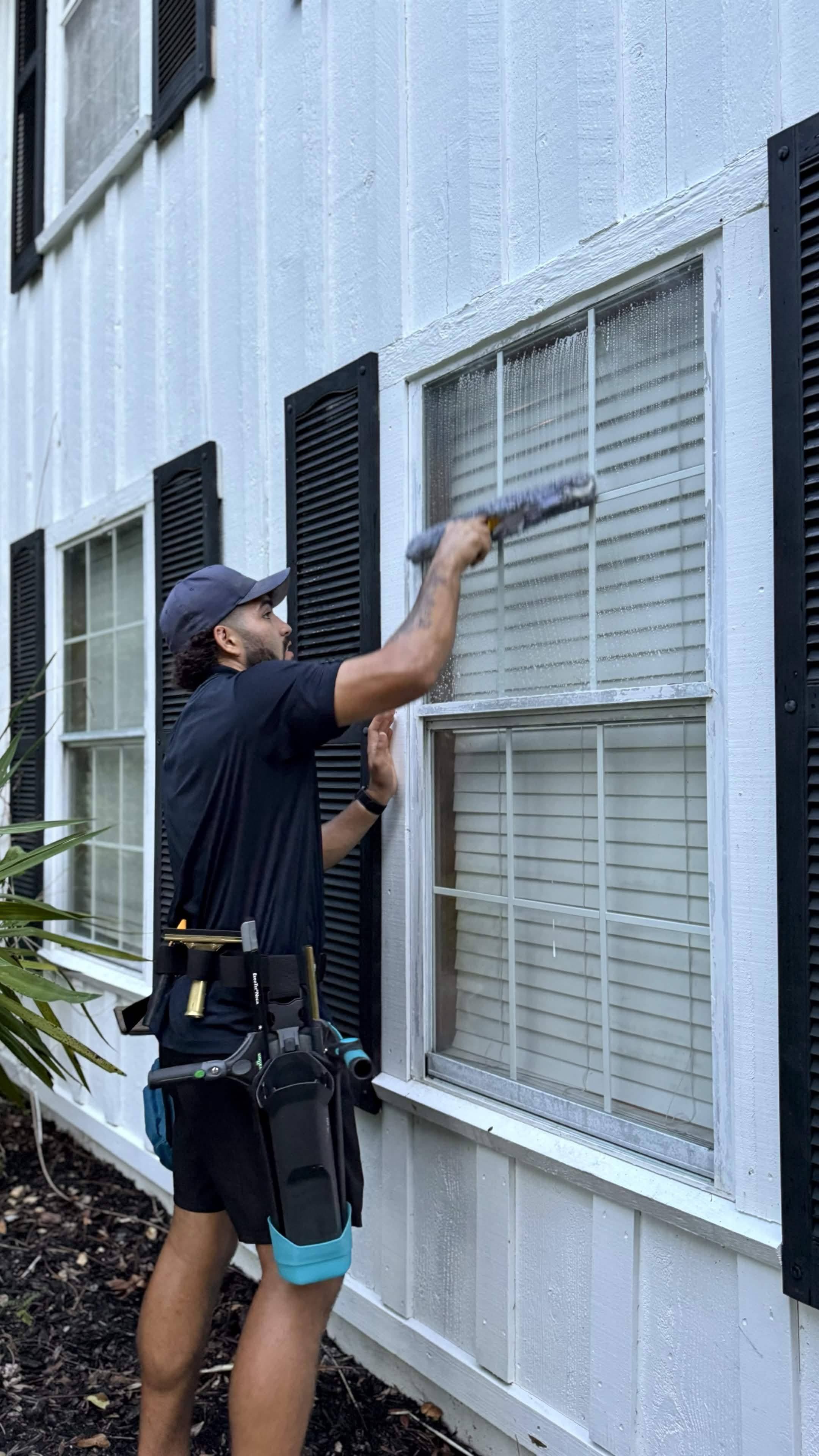 CrestFlow technician soaping down an exterior window with a microfiber applicator