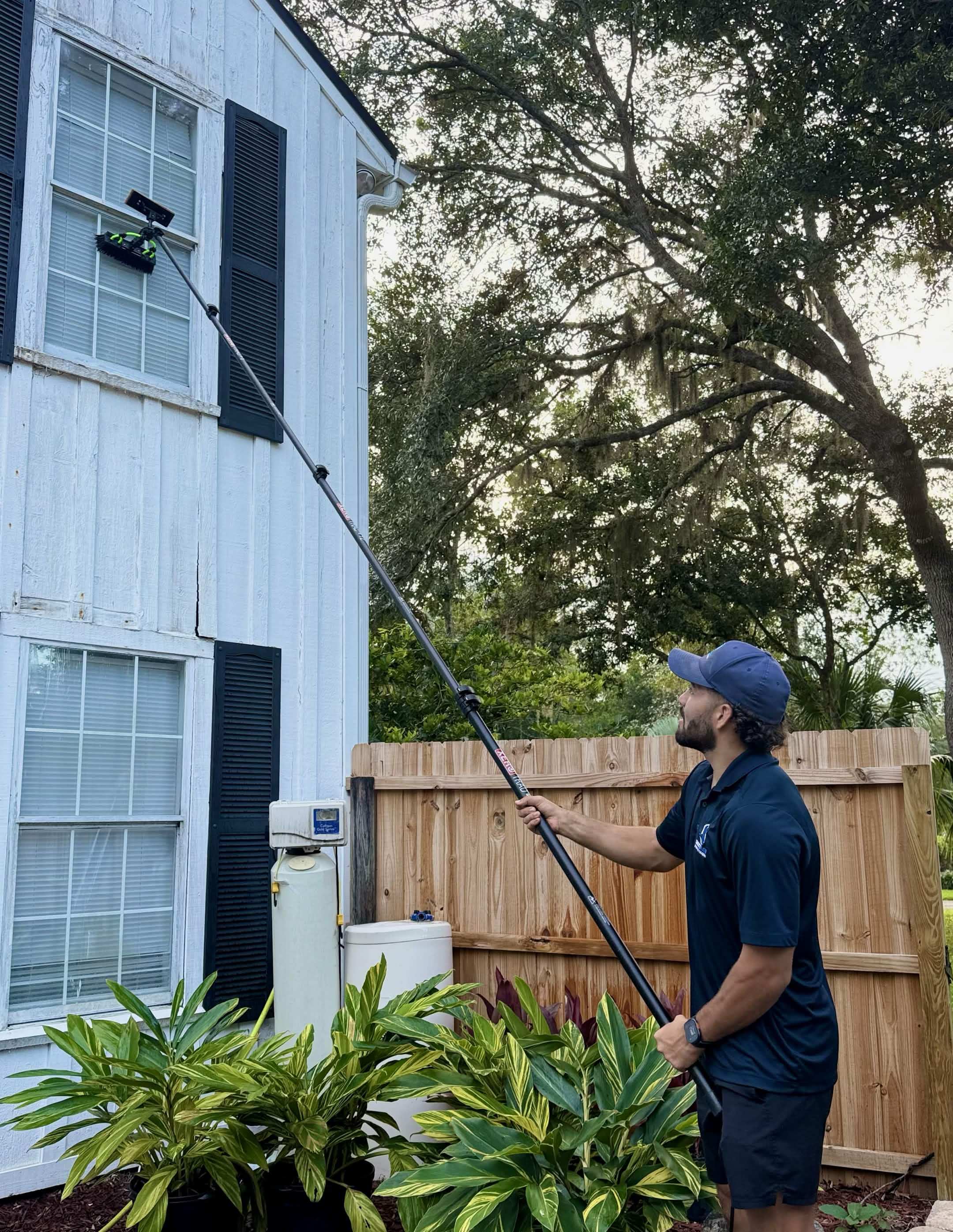 CrestFlow technician using a water-fed pole to clean second-story windows on a Florida home